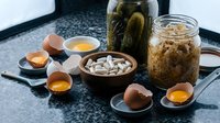Fermented foods collection with sauerkraut, pickles and broken eggshells on kitchen counter. Probiotic ingredients for healthy gut microbiome and digestion.