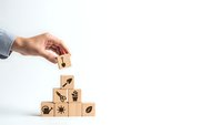 Business hand placing wooden cube with growth arrow on stack of blocks with nature icons representing sustainable development and eco-friendly progress.