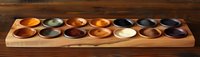 Handcrafted wooden mancala board game with colorful stone pieces arranged in carved pockets on rustic wooden table, traditional African strategy game setup.