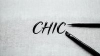 Calligraphy brush pens writing the word chic on white textured paper, suitable for design, branding, typography, and creative projects.