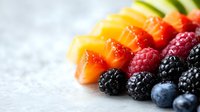 Fresh colorful fruit arrangement with mango cubes, raspberries, blackberries and blueberries on light background, selective focus with copy space.