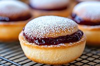 Sweet donut filled with chocolate cream and dusted with powdered sugar on cooling rack, macro food photography with selective focus and blurred background.