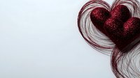 Red glittery heart decoration with flowing hair strands creating heart shape against white background, romantic Valentine's Day concept for greeting cards and designs.