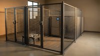 Industrial metal wire mesh storage cages in warehouse facility for secure equipment and inventory organization in commercial building interior.