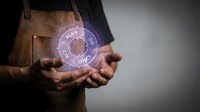 Craftsman holding glowing holographic plan icon with zodiac wheel symbols, representing digital design, astrology consultation, and futuristic technology integration for business and creative projects.