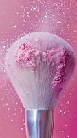 Makeup brush with pink powder explosion against pink background, creating dynamic motion of cosmetic particles for beauty and cosmetics advertising.