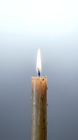 Single burning candle with melted wax drips and bright flame against soft gradient background for meditation and relaxation concepts.