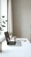 Minimalist workspace with laptop, coffee mug, notebook, and potted plant on white desk by window with natural light and linen curtains for remote work and productivity.