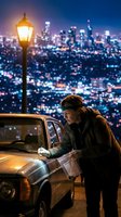 Young man reading map beside vintage car at night overlooking illuminated city skyline with street lamp creating atmospheric urban scene for travel concepts.