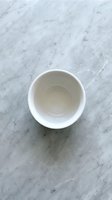 Empty white ceramic bowl on marble surface, overhead view. Minimalist kitchen styling with natural stone texture background, suitable for food photography, culinary content, tableware design, and home decor projects.