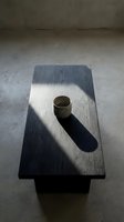 Empty metal cup on wooden board casting shadow on concrete floor in minimalist interior space for design and architectural projects.