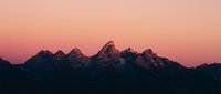 Dramatic mountain silhouette against pink and orange sunset sky, creating moody landscape scenery for nature and travel projects.