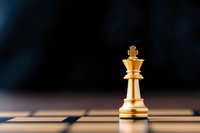 Golden king chess piece standing alone on board with dramatic lighting and shadow pattern, symbolizing leadership, strategy and power in business concept.