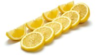 Fresh lemon slices and wedges arranged in a diagonal row on a white background, showcasing vibrant yellow citrus fruit for food and beverage design.