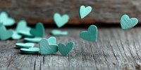 Mint green heart shapes scattered on rustic wooden surface, creating romantic atmosphere for wedding decorations, Valentine's Day cards, or love-themed designs.