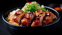 Grilled eel glazed with sweet teriyaki sauce served over steamed rice in traditional black ceramic bowl with fresh green onion garnish for Asian cuisine menu.