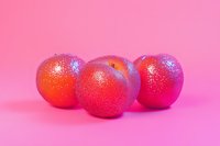 Fresh ripe red apples with water droplets on vibrant pink background, minimal food composition for healthy lifestyle and natural product advertising.