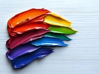 Vibrant rainbow colored oil paint strokes arranged in spectrum order on white textured background, showing thick impasto technique and glossy texture for artistic designs.