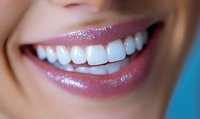Close up of bright white healthy teeth and glossy pink lips with sparkly lip gloss against blue background, showing genuine happy smile. Perfect for dental care ads.