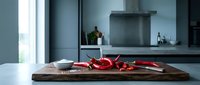 Modern kitchen interior with red chili peppers on wooden cutting board, contemporary design with gray cabinets and natural lighting for culinary content.