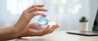 Male hands holding glowing crystal sphere with digital light effect on office desk, representing future technology, innovation, and business solutions for corporate presentations.