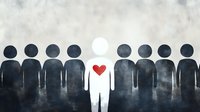 White figure with red heart stands out among dark silhouettes representing individuality, love, compassion and human connection in diverse group.