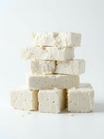 Stacked white tofu blocks with visible texture and crumbles isolated on neutral background, ready for food and culinary design projects.