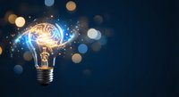 Glowing light bulb with brain inside radiating sparks and energy on dark blue background with bokeh lights for innovation and creativity concepts.