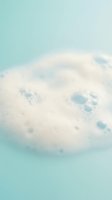 White bath bomb fizzing and dissolving in turquoise water creating bubbles and foam for spa relaxation and self-care wellness routine at home.