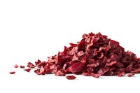 Pile of crushed red metallic fragments scattered on white surface, shimmering with reflective surfaces and angular shapes, isolated on pure white background.