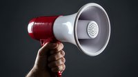 Red and white megaphone held in hand against dark background, isolated for announcement, promotion, marketing communication and broadcasting design projects.