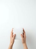 Hands holding blank white box against neutral background, product packaging mockup for branding and marketing materials.