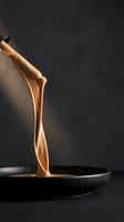 Golden motor oil pouring from metal can into dark pan against black background, showcasing fluid dynamics and industrial lubrication for automotive and mechanical applications.