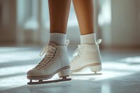 Female legs in white figure skates and knitted socks standing on ice in soft natural light. Close-up view capturing winter sports elegance and graceful skating atmosphere.
