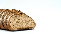 Freshly sliced whole grain bread loaf with seeds and nuts on white background, healthy artisan bakery product for breakfast and sandwiches.