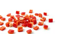 Fresh red bell pepper diced into small cubes scattered on white background. Chopped vegetable ingredient for cooking, salads and meal preparation.