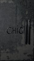 Chic word formed with paintbrushes on dark textured fabric background, flat lay composition for art, design, and creative industry concepts.