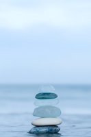 Zen stone stack balanced on water surface with ocean horizon background for meditation wellness and mindfulness concepts.