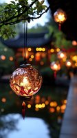 Glowing oriental lantern with intricate floral pattern hanging in garden at dusk, soft bokeh lights creating magical atmosphere against traditional architecture.