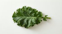 Fresh green kale leaf with water droplets isolated on white background, suitable for healthy eating, nutrition, organic food, and culinary design projects.