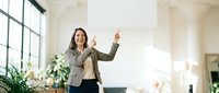 Happy businesswoman celebrating success with raised arms in modern office space with large windows and natural light.