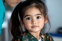 Portrait of young Asian girl with dark ponytail wearing floral dress, looking at camera with gentle smile and innocent expression. Natural lighting highlights soft features.