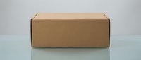 Closed brown cardboard shipping box on a reflective surface with gray background, for packaging, delivery, and e-commerce concepts.