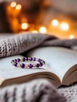 Amethyst beaded bracelet resting on open book with cozy knit blanket and warm bokeh lights, perfect for wellness, spirituality, and lifestyle content.