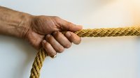 Elderly hand gripping golden rope symbolizing strength, perseverance and determination in overcoming life challenges and obstacles.