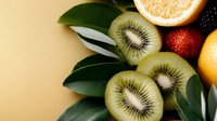 Sliced kiwi fruit with citrus and pomegranate on neutral background, suitable for food styling, recipe blogs, and healthy eating content.