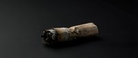 Burnt cigarette butt with ash on dark background showing smoking addiction and health risks concept for anti-smoking campaigns and tobacco awareness.