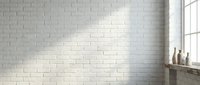 White brick wall interior with natural sunlight streaming through window creating soft shadows and warm atmosphere for modern home design.