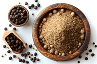 Ground and whole black peppercorns in rustic wooden bowls on white background, overhead view of aromatic spices for cooking and seasoning food preparation.