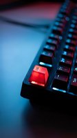 Red escape key on black keyboard with dramatic blue lighting for technology and cybersecurity concepts.
